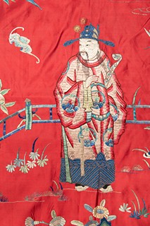 Dekorativní čínský textilní panel na červeném hedvábném podkladu, bohatě zdobený vícebarevnou výšivkou s figurálními motivy. | Čína