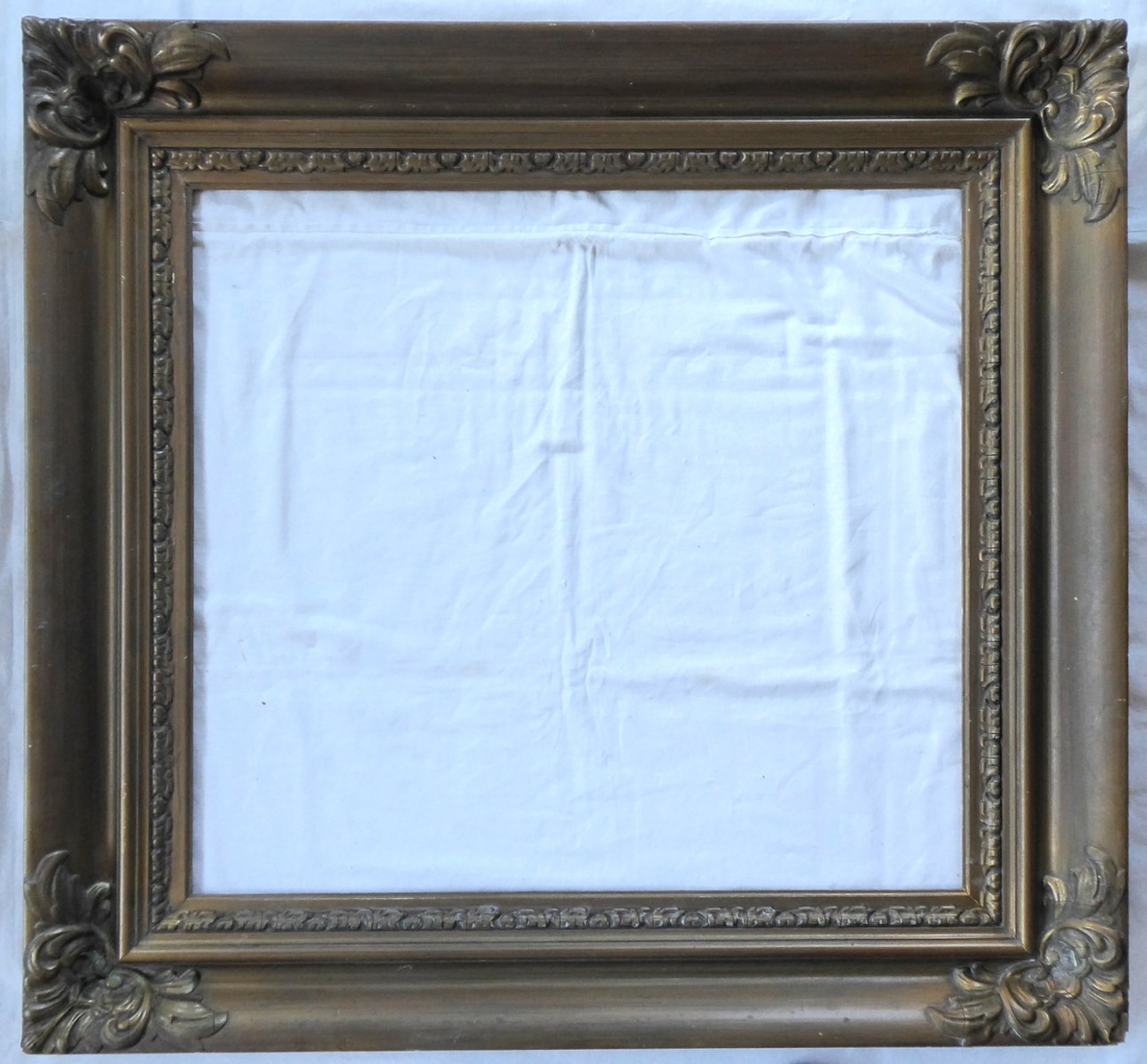 Široký zlatý patinovaný rám s ozdobami a ornamentální vnitřní lištou čtvercového tvaru